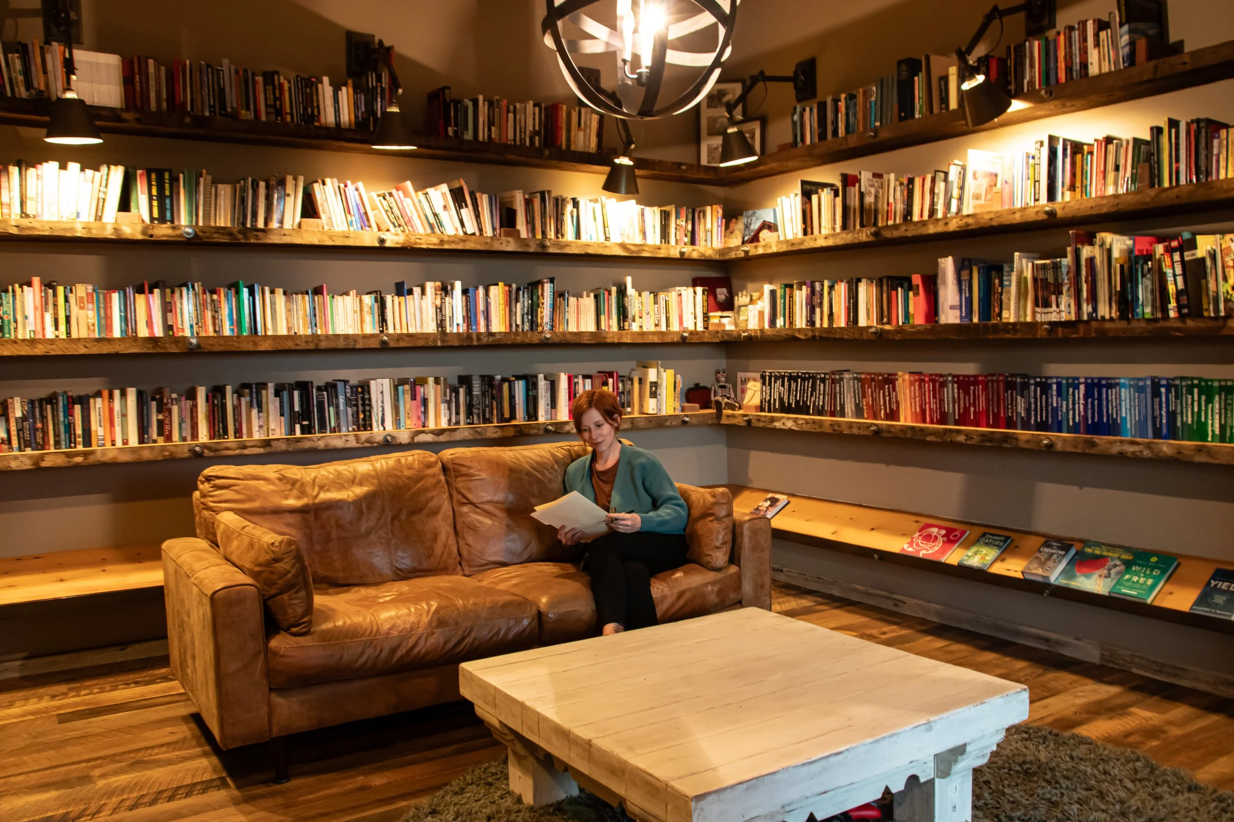 Sara Beckner reading a chart on a leather sofa in her book-lined study in Grand Junction, Colorado
